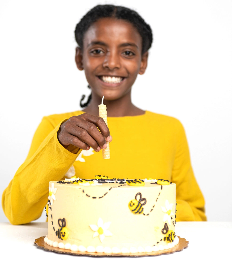 A child placing a Beeswax Candle Kit candle on a birthday cake.