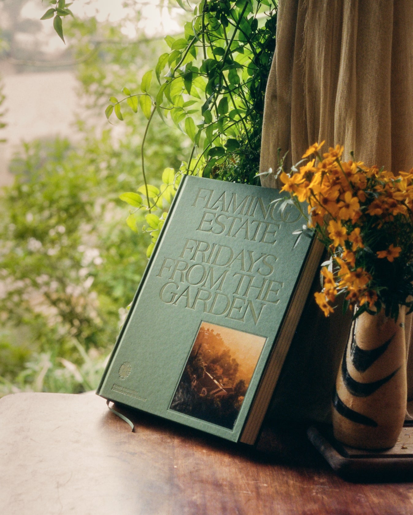 Flamingo Estate Fridays From the Garden Cookbook on a wooden shelf.