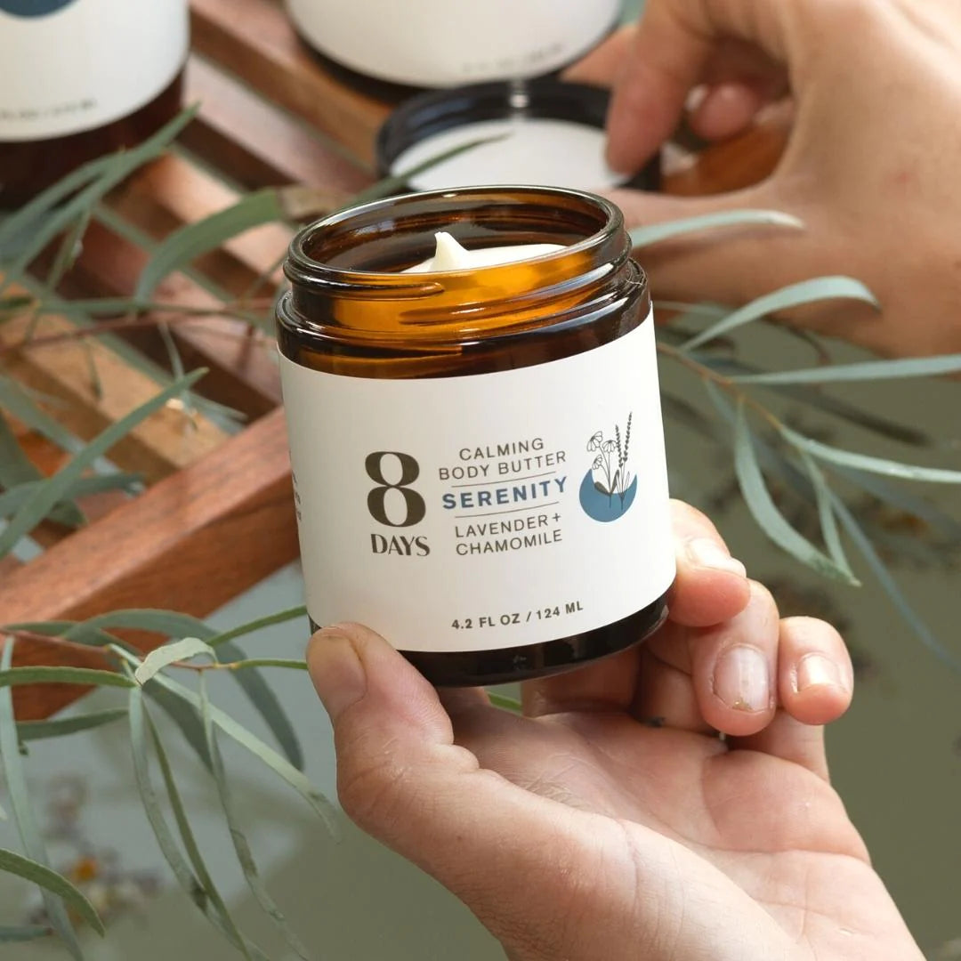 Hand holding 8 Days Botanicals Organic Body Butter - Serenity over a bath..